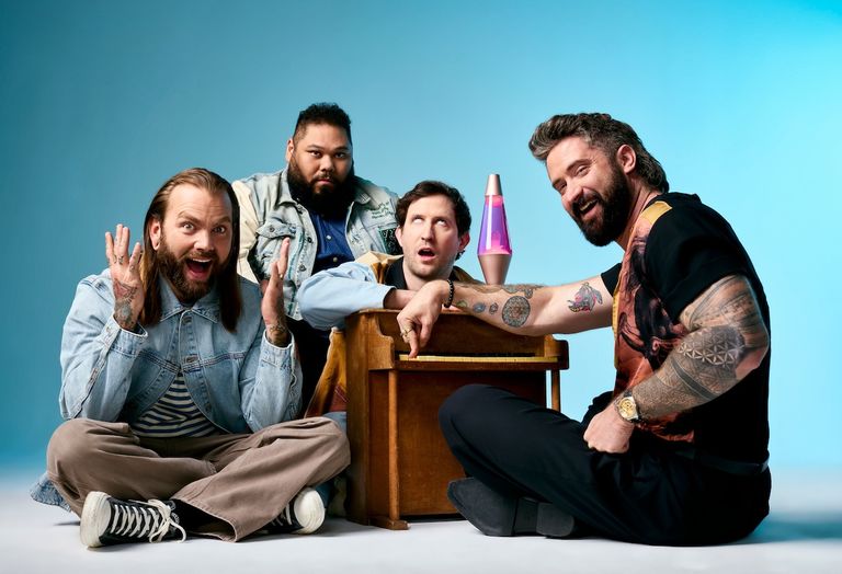 Post-hardcore band Dance Gavin Dance members posing expressively around a miniature piano and lava lamp against a blue background.